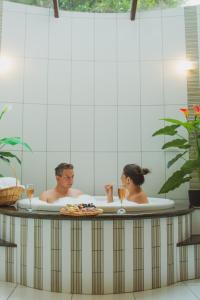 um homem e uma mulher numa banheira com um prato de comida em Pousada Medeiros em Monte Verde