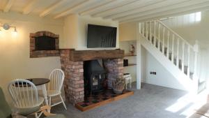 a living room with a fireplace with a tv on top at Barley Cottage - 5* Cyfie Farm with log burner and private covered hot tub in Llanfyllin