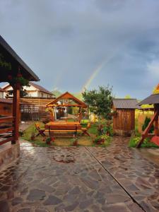 a rainbow in the background of a patio with a bench at Pensiunea Adriana in Vadu Izei