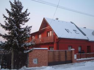 a red house with a fence and a tree at Apartman U Adamov in Liptovský Mikuláš
