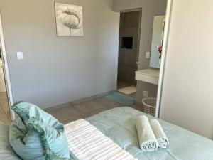 a bedroom with a bed with towels and a shower at Langebaan Holiday Home in Langebaan