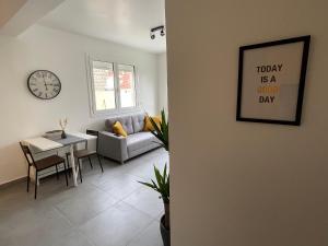 a living room with a couch and a table and a clock at Superbe T2 proche de Paris & Disneyland in Ozoir-la-Ferrière +2 photos