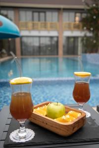 a tray of fruit and two drinks on a table next to a pool at Mandarinnart HOTEL in Astara