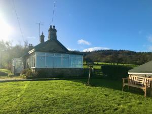 a house with a blue window in a field at Leazes Cottage in Rothbury