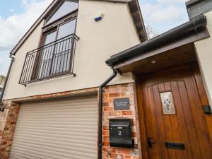 uma garagem com uma porta de garagem e um edifício em The Coach House em Cheltenham