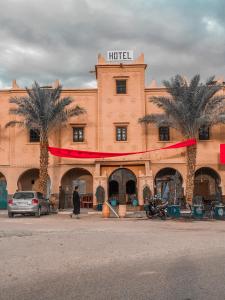 a hotel with palm trees in front of a building at Kasbah Ennakb in Nkob