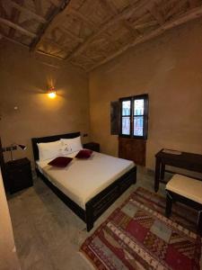- une chambre avec un lit blanc et une fenêtre dans l'établissement Kasbah Ennakb, à Nkob