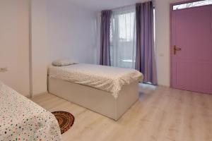 - une chambre avec un lit et une porte violette dans l'établissement Pensiune Arada, à Arad