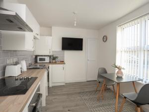a kitchen with white cabinets and a table with chairs at Port Apartment 1 in Holyhead