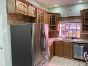 een keuken met een roestvrijstalen koelkast en houten kasten bij Beverley Manor DIAMOND VALE' 2 Bedroom 1 Bath Apartment in Diego Martin
