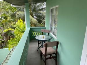 balcón con 2 sillas, mesa y ventana en Beverley Manor DIAMOND VALE' 2 Bedroom 1 Bath Apartment en Diego Martin