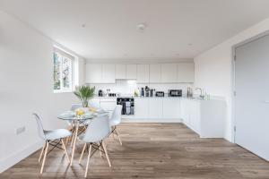 a kitchen with white cabinets and a table and chairs at Azure in Bournemouth