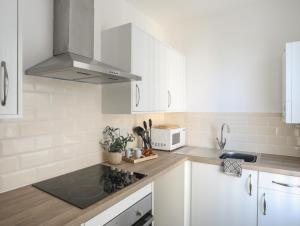 eine weiße Küche mit einer Spüle und einer Mikrowelle in der Unterkunft Port Apartment 2 in Holyhead