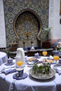 einen Tisch mit Teller mit Lebensmitteln und Gläsern Orangensaft in der Unterkunft Dar Fez Arabic in Fès