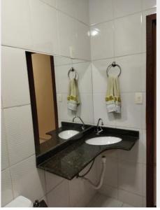 a bathroom with two sinks and a mirror at Apartamento de luxo com 2 quartos, sala com sacada, cozinha área de serviço e 1 banheiro social. in Ipatinga