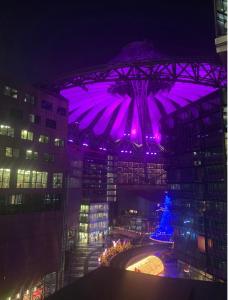a large building with purple lighting in a city at night at Fairytale in Sony Center Berlin in Berlin