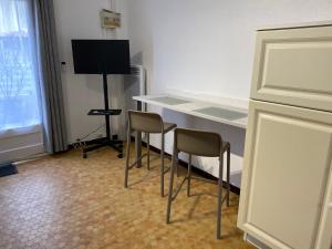 Cette chambre comprend deux chaises, un bureau et une télévision. dans l'établissement Au cœur de la Cotinière Studio en résidence parking privé wifi, à La Cotinière