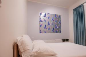 1 cama con almohadas blancas y una pintura en la pared en Centrale cozy home, en Ioannina