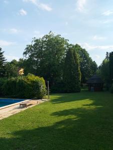 a park with a bench in the grass next to a pool at Zsuzsa Apartmanház in Sukoró