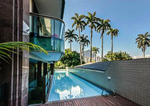 a swimming pool next to a building with palm trees at Flat - Leblon in Rio de Janeiro
