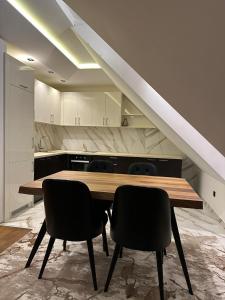 uma cozinha com uma mesa de madeira e 2 cadeiras em Apartman GLECER KOP em Kopaonik