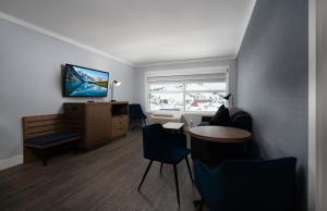 um quarto com uma secretária, cadeiras e uma televisão em Prestige Kamloops Hotel em Kamloops