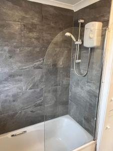 a shower with a glass door and a tub at Rhyl beach town apartment in Rhyl