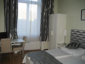 a bedroom with a bed and a desk and a window at Pension Schottentor in Vienna