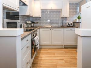 a kitchen with white cabinets and wood floors at Bythynnod Newydd in Trefor