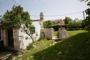 an old stone house with a tree in the yard at Holiday Home Mihovilovic in Premantura