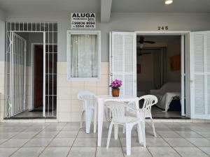- une table et des chaises blanches sur la terrasse dans l'établissement RESIDENCIAL COM CASAS DE 3 DORM, à Garopaba
