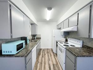 a kitchen with white appliances and a blue microwave at Lovely Apartment Unit Near Central Coalinga in Coalinga