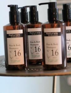 four bottles of hair and body shampoo sitting on a shelf at Les appartements du Domaine de Maffliers 4 étoiles - Demeures de Campagne in Maffliers