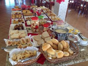 a buffet of food with baskets of bread and pastries at Pousada e Restaurante Kambuká in Mucuri