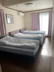 3 Betten in einem Zimmer mit rosa Vorhängen in der Unterkunft Azuma Taku - Vacation STAY 13741 in Kanie