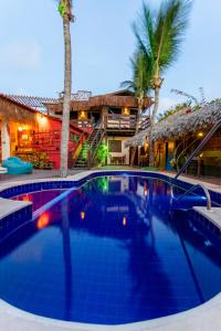 uma piscina em frente a uma casa com palmeiras em Pousada La Vie Jeri em Jericoacoara