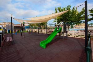 a playground with a green slide and a canopy at Holiday Beach Brissa Mar in Gran Alacant