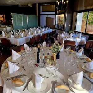 uma sala de jantar com mesas com toalhas de mesa brancas e copos em Hotel Bruc em El Bruc