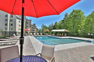 a red umbrella sitting next to a swimming pool at Mountain Green Resort by Killington VR - 2 Bedrooms in Killington
