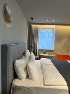 a bedroom with a bed with white pillows and a window at The Grey Design Hotel in Dortmund