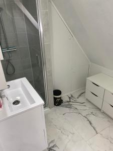 y baño blanco con lavabo y ducha. en Chambre rustique avec double lit et sa salle de bain privée, en Urbès