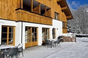 un patio avec des tables et des chaises en face d'un bâtiment dans l'établissement Apartmenthaus Matri, à Wald am Arlberg