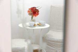 a white table with two cups and a vase with flowers at Dream City Rome in Rome