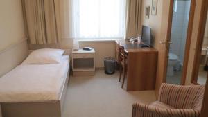 a small hotel room with a bed and a desk at Pension Thiel in Bad Schwartau