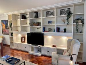 a living room with white shelves and a television at Atico al lado del Ayuntamiento in Oviedo