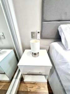 a white nightstand next to a bed in a room at Flat 2 quartos a 2 quadras da paulista com garagem in São Paulo