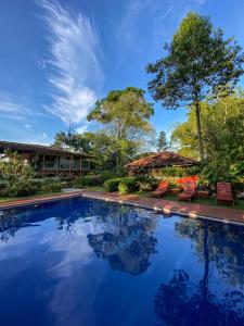 einen Pool in einem Resort mit Stühlen und Bäumen in der Unterkunft Hacienda Bambusa in El Caimo
