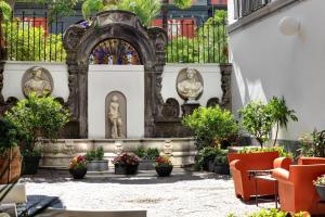 a courtyard with statues and plants in a building at Hotel Piazza Bellini & Apartments in Naples