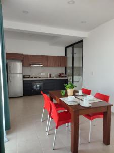 a kitchen with a wooden table and red chairs at LOMAS AEROPUERTO in San Agustin de las Juntas