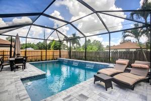 uma piscina com duas espreguiçadeiras e uma mesa em Naples Home with Lanai and Pool Near Vanderbilt Beach! em Naples